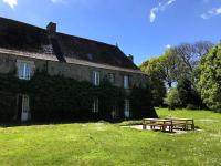 a building with two picnic tables in front of it at Manoir le Cosquer in Pommerit-le-Vicomte