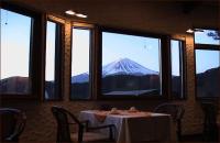 a table with a view of a mountain through windows at Guesthouse Sakuya in Fujikawaguchiko