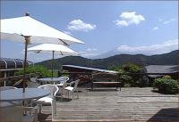 a deck with tables and chairs and an umbrella at Guesthouse Sakuya in Fujikawaguchiko