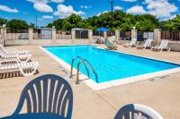 una piscina con sillas blancas en Motel 6-Cleburne, TX, en Cleburne