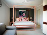 Un dormitorio con una cama con dosel y almohadas rojas. en Mogi Boutique Hotel, en Ezulwini