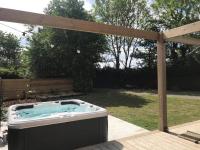 a hot tub in a backyard with a wooden pergola at Le Ristouar Spa forêt et mer in Quimperlé