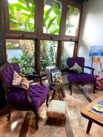 a living room with purple chairs and a large window at Pousada Arte Urquijo in Paraty