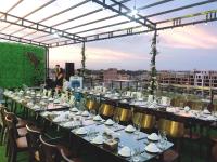 Una mesa larga con platos y sillas blancas sobre un techo. en Melanta Hotel - FLC Sầm Sơn, en Sầm Sơn