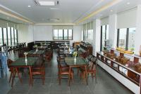 Un comedor con mesas y sillas y ventanas. en Melanta Hotel - FLC Sầm Sơn, en Sầm Sơn