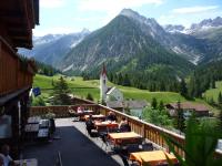 un balcone con tavoli e sedie con vista sulle montagne sullo sfondo di Gasthaus Alpenrose a Gramais