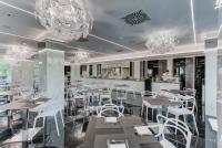 a restaurant with white chairs and tables and chandeliers at Hotel Due Mari & SPA in Rimini