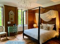 a bedroom with a canopy bed and a table and window at LA MEFFRAIS 1741 in Dinan