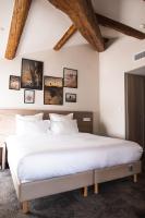 a bedroom with a large white bed with pictures on the wall at Hôtel 1770 &amp; Spa in Le Pontet