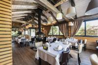 Un restaurante con mesas y sillas blancas y grandes ventanales. en Lakeside Hotel Plitvice, en Lagos de Plitvice