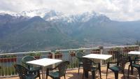 un balcón con mesas y sillas con montañas en el fondo en Hotel Mirabeau, en Bellagio