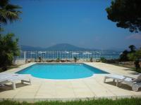 a swimming pool with two white chairs and the ocean at Villa Playa del Sol -B4 in Saint-Tropez