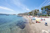einen Strand mit Menschen auf Sand und Wasser in der Unterkunft Modern apartment 2 bedrooms quiet terrace in a palm beach area, 30 meters from seaside in Cannes