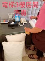 a woman standing at a desk with a phone and pillows at Dryad Motel in Tainan
