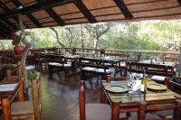 a restaurant with wooden tables and chairs and trees at Jabula Kruger Safari Lodge in Marloth Park