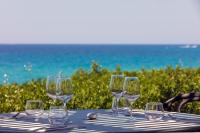 een groep wijnglazen op een tafel bij de oceaan bij Hotel Le Ruesco in Olmeto