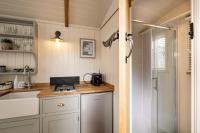 a kitchen with white cabinets and a sink and a shower at Trevone Luxury Shepherds hut close to the beach in Saint Merryn