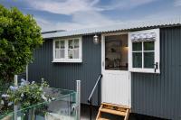 a green shed with a white door and windows at Trevone Luxury Shepherds hut close to the beach in Saint Merryn