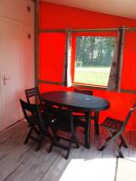 a table and chairs in a room with a red wall at Camping le Clos de Balleroy in Balleroy