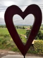 a heart shaped window with a view of a field at La Pause in Plombières