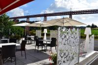 a patio with tables and chairs and umbrellas at Logis Hôtel Beau Site in Loubaresse
