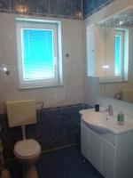 La salle de bains est pourvue de toilettes, d&#39;un lavabo et d&#39;une fenêtre. dans l&#39;établissement Apartments Delfini, à Sveti Filip i Jakov