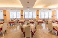 ein Restaurant mit weißen Tischen und Stühlen und Fenstern in der Unterkunft Hotel Nobel in Rimini