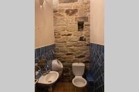 a bathroom with two toilets and a sink and a stone wall at Ancien Moulin rénové à neuf pour 20 personnes sur les rives du Trieux in Plésidy