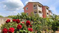 a house with red roses in front of it at Apartment in Malinska&#47;Insel Krk 13118 in Sveti Vid-Miholjice