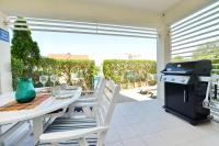 a patio with a table and chairs and a grill at Apartman Ema Dobropoljana in Dobropoljana