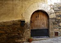 Un antiguo edificio de piedra con una puerta de madera. en Dos Arcos Usana, en Aínsa