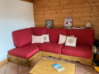 a red couch in a living room with a table at Les Alpages de Reberty in Les Menuires