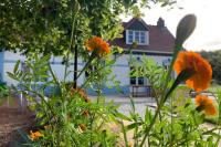 a garden with orange flowers in front of a house at Le Moulin de la Planquette in Cavron-Saint-Martin