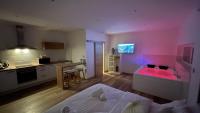 a room with a bed and a kitchen with pink lighting at Studio Balnéothérapie in Wintzenheim