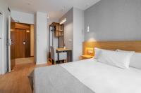 Un dormitorio con una cama blanca y un escritorio. en Hotel Condado Ourense, en Ourense