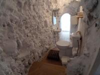 a bathroom with a toilet and a stone wall at Casa Cueva “La Estrella” in Granada