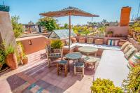 a patio with a table and chairs and an umbrella at Riad Chorfa in Marrakesh
