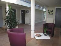 a lobby with purple chairs and a table and a column at Hôtel L&#39;ile Du Saussay in Itteville