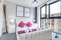a white bed with pink pillows in a room with windows at City View Apartments Birmingham City Centre in Birmingham