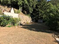 a dirt yard with a stone wall and trees at BEL APPARTEMENT TYPE F3 in Amélie-les-Bains-Palalda