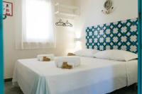 Un dormitorio con una gran cama blanca con cabecero azul. en Albarìa Favignana Apartments, en Favignana