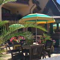 a patio with tables and chairs and an umbrella at Hotel Le Mandelberg in Mittelwihr