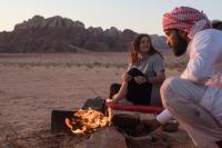 Dos personas sentadas alrededor de un fuego en el desierto. en Wadi Rum Desert Home, en Wadi Rum