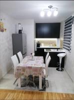 a dining room with a table and chairs and a kitchen at Nenadovic Apartman in Obrenovac