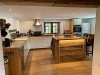 a large kitchen with white cabinets and a wooden island at Beautiful renovated chalet near ski resort France in Arâches-la-Frasse