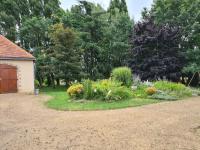 a garden with flowers and a building and trees at Maison de vacances Daumeray in Daumeray