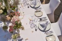 a white table with plates and flowers on it at A-ROSA Kurhaus Binz in Binz