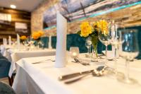 a table with white tables with yellow flowers on it at Hotel Blinkfüer in Dierhagen