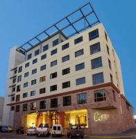 Un gran edificio con coches aparcados delante. en Austral Plaza Hotel, en Comodoro Rivadavia
