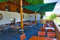 un restaurante con mesas, sillas y una sombrilla verde en Hotel Gasthof Altmann, en Warzenried